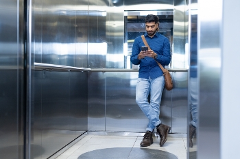 using-smartphone-man-standing-elevator-wearing-casual-business-attire-copy-space